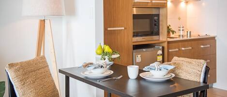 Una cucina moderna con mobili in legno, un forno a microonde e un tavolo da pranzo apparecchiato con piatti, ciotole e una tazza.