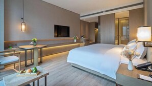 Una habitación de hotel moderna con una cama grande, una mesita de noche, una lámpara y un televisor de pantalla plana montado en la pared.