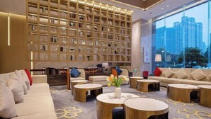 Un moderno vestíbulo de hotel con una amplia estantería, asientos cómodos y vistas a la ciudad.