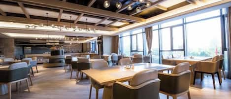 A modern restaurant with high ceilings, pendant lighting, and large windows.