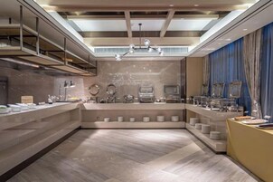 Un moderno vestíbulo de hotel con un mostrador de recepción central, una araña de cristal y un alto techo con tragaluces.