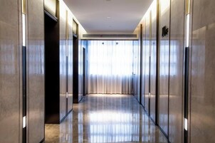 Un pasillo con piso reflectante, puertas a ambos lados y una ventana al final.