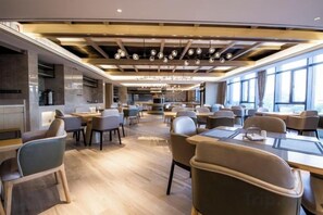 A spacious dining area with multiple tables and chairs, a modern ceiling design with exposed beams, and large windows providing natural light. - Huake Xinyi Hotel (Zhuzhou)