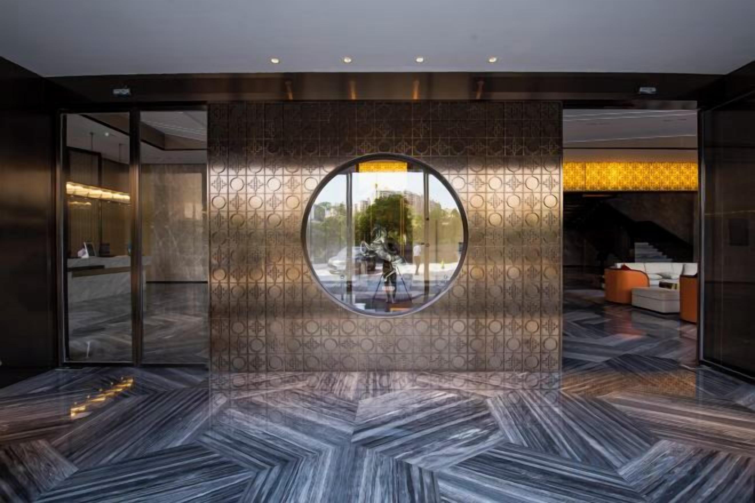 A lobby with a circular window, a reception desk, and a patterned floor.
