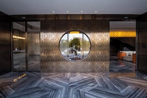 Una hall con una finestra circolare, una reception e un pavimento decorato.