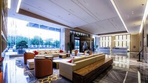 Un moderno vestíbulo de hotel con una amplia zona de estar, grandes ventanales que ofrecen vistas al exterior y una recepción.