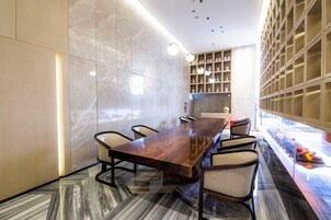 Una sala de conferencias moderna con una larga mesa de madera, sillas cómodas y piso de mármol.