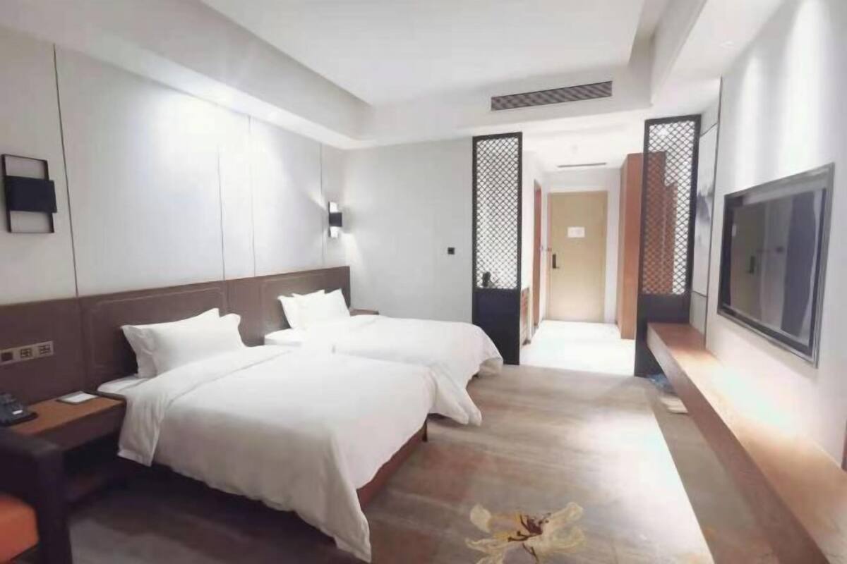 A hotel room with two beds, a TV, a desk, and a walk-in closet.