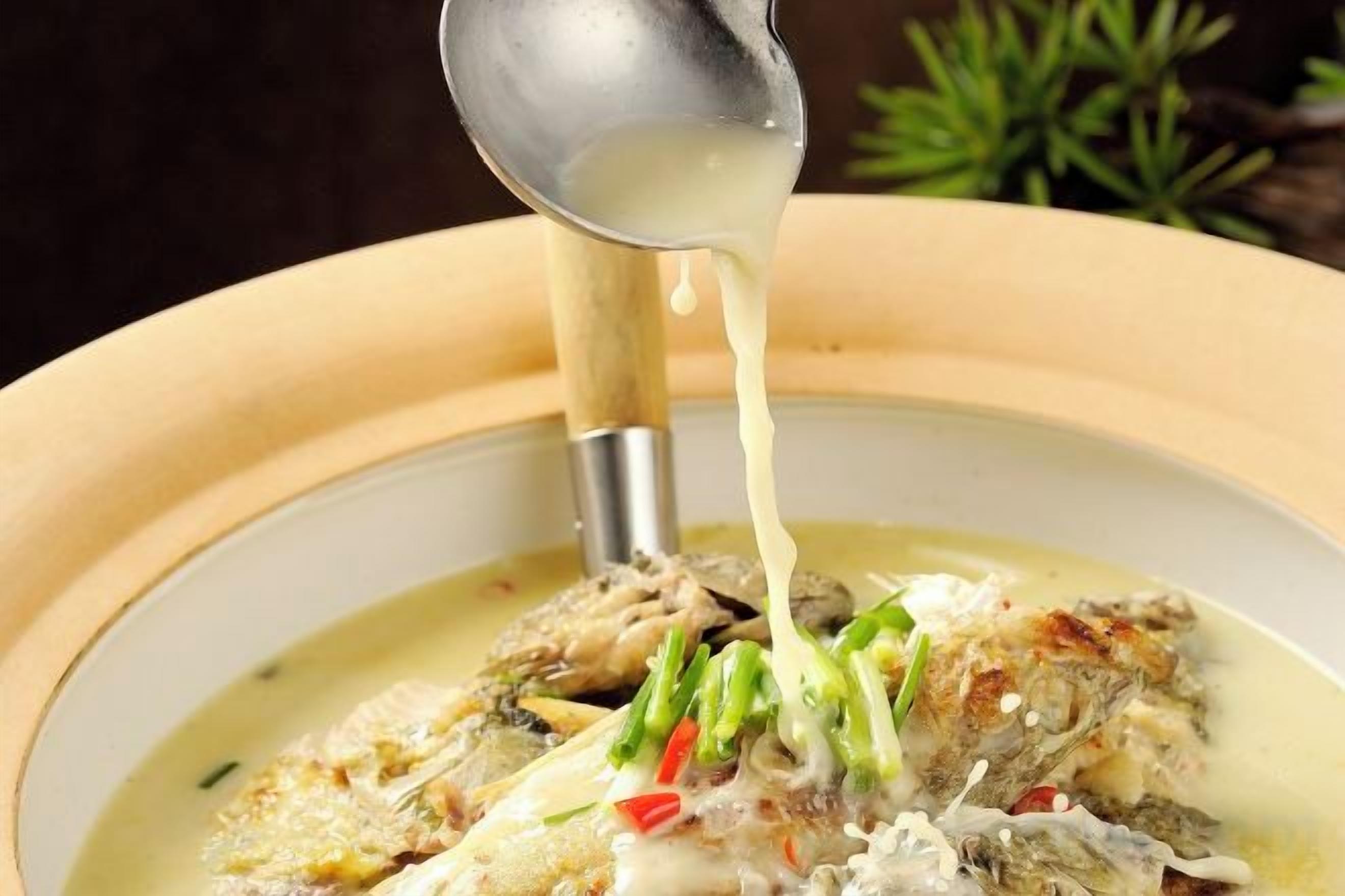 A bowl of soup with a ladle pouring broth.