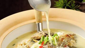 A bowl of soup with a ladle pouring broth.