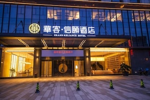 Exterior del hotel Grand Reliance, con fachada moderna y entrada iluminada.