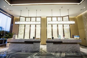 Un área de recepción con mostradores de mármol, iluminación colgante y vistas al exterior.