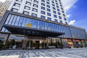 A modern hotel with a prominent sign, large windows, and a tiled entrance area. - Huake Xinyi Hotel (Zhuzhou)
