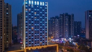 Un edificio alto con ventanas iluminadas y un área de entrada bien iluminada.