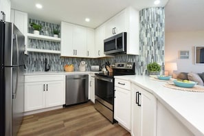 Una cocina moderna con armarios blancos, electrodomésticos de acero inoxidable y salpicadero de azulejos.