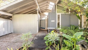 A covered patio area with a wooden deck, potted plants, and a small table. - Aptos Beach Retreat Hot Tub & 5 Min Walk to Sand (Aptos)