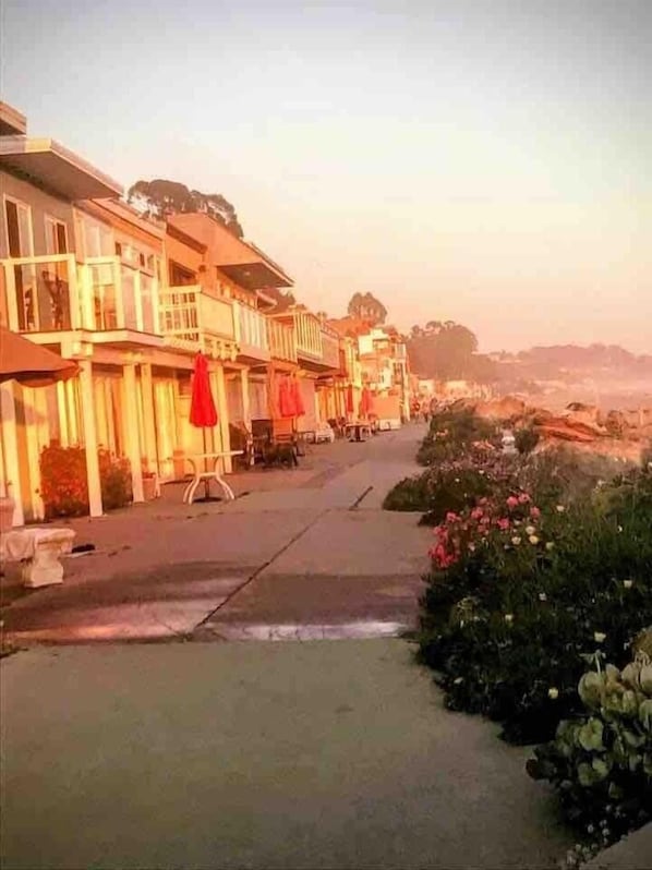 A street lined with multi-story buildings, some with balconies and outdoor seating.