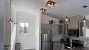 Una cocina moderna con electrodomésticos de acero inoxidable, encimera de mármol e iluminación colgante.