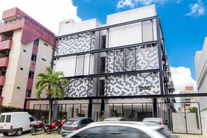A modern building with a glass facade, multiple balconies, and a gated entrance.