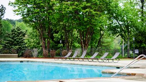 Una piscina con sillones de descanso y una valla de metal.