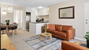 A modern apartment with a kitchen, dining area, and living room. - Modern Luxurious Living With Your Own Parking Spot (Sandy Bay)