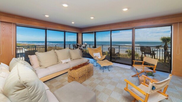 Un balcon spacieux offrant une vue sur l’océan, aménagé avec un canapé, des fauteuils et une petite table.