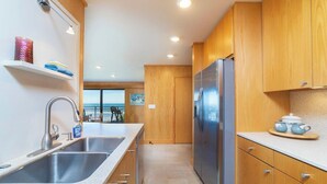 Une cuisine moderne avec des meubles en bois, des appareils électroménagers en acier inoxydable et une vue sur l’extérieur.