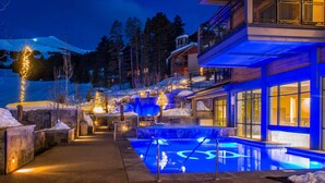 Un bâtiment moderne doté d’un espace piscine, entouré de neige et d’arbres.