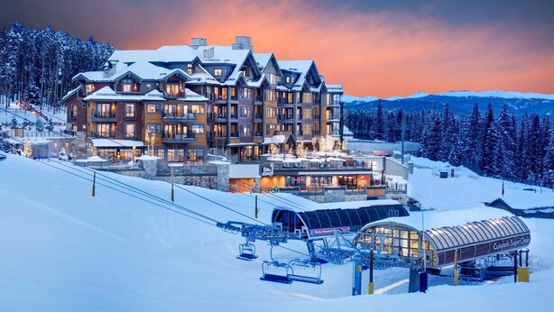 Un grand chalet à plusieurs étages, avec un télésiège visible au premier plan.