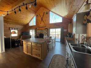 Cozy living area with a stone fireplace, wooden chairs, and a dining table.
