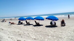 A beach with several blue umbrellas and beach chairs. - Luxury Ocean Front (Murrells Inlet)