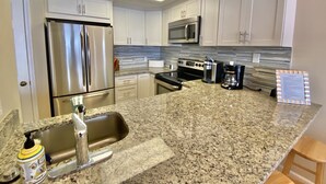 A modern kitchen with stainless steel appliances, granite countertops, and white cabinetry. - Luxury Ocean Front (Murrells Inlet)