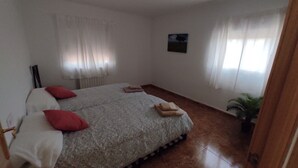 Une chambre à coucher avec un lit, des oreillers, une petite table et une plante en pot.