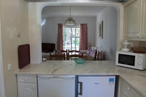 A compact kitchen with a microwave, a small refrigerator, and a dining area with a table and chairs.