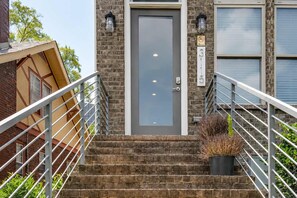 A building entrance with a metal staircase, a door, and a brick wall. - Nashville Getaway • Walk to Broadway & Vandy (Nashville)