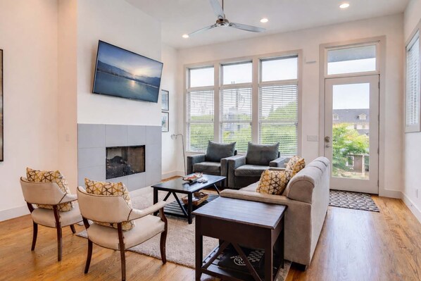A living room with a fireplace, seating area, and large windows.