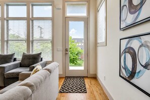A living room with a sofa, a door leading outside, and abstract art on the wall. - Nashville Getaway • Walk to Broadway & Vandy (Nashville)