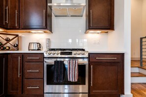 A kitchen with dark wooden cabinets, a stainless steel stove, and a tiled backsplash.