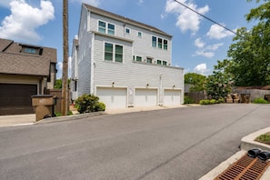 A two-story residential building with a garage, a driveway, and a street.