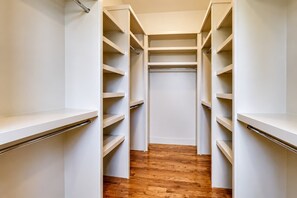 Un vestidor amplio con varias estanterías y piso de madera.