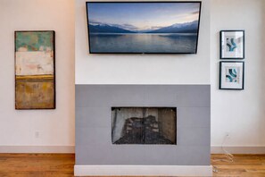 A modern living room with a fireplace, a mounted television, and abstract art on the walls.