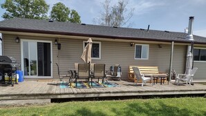 Une maison avec une terrasse, du mobilier d’extérieur et un barbecue.