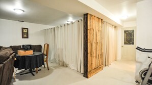 Une pièce comprenant une table ronde, un meuble en bois, une chaise et une grande cloison en bois.