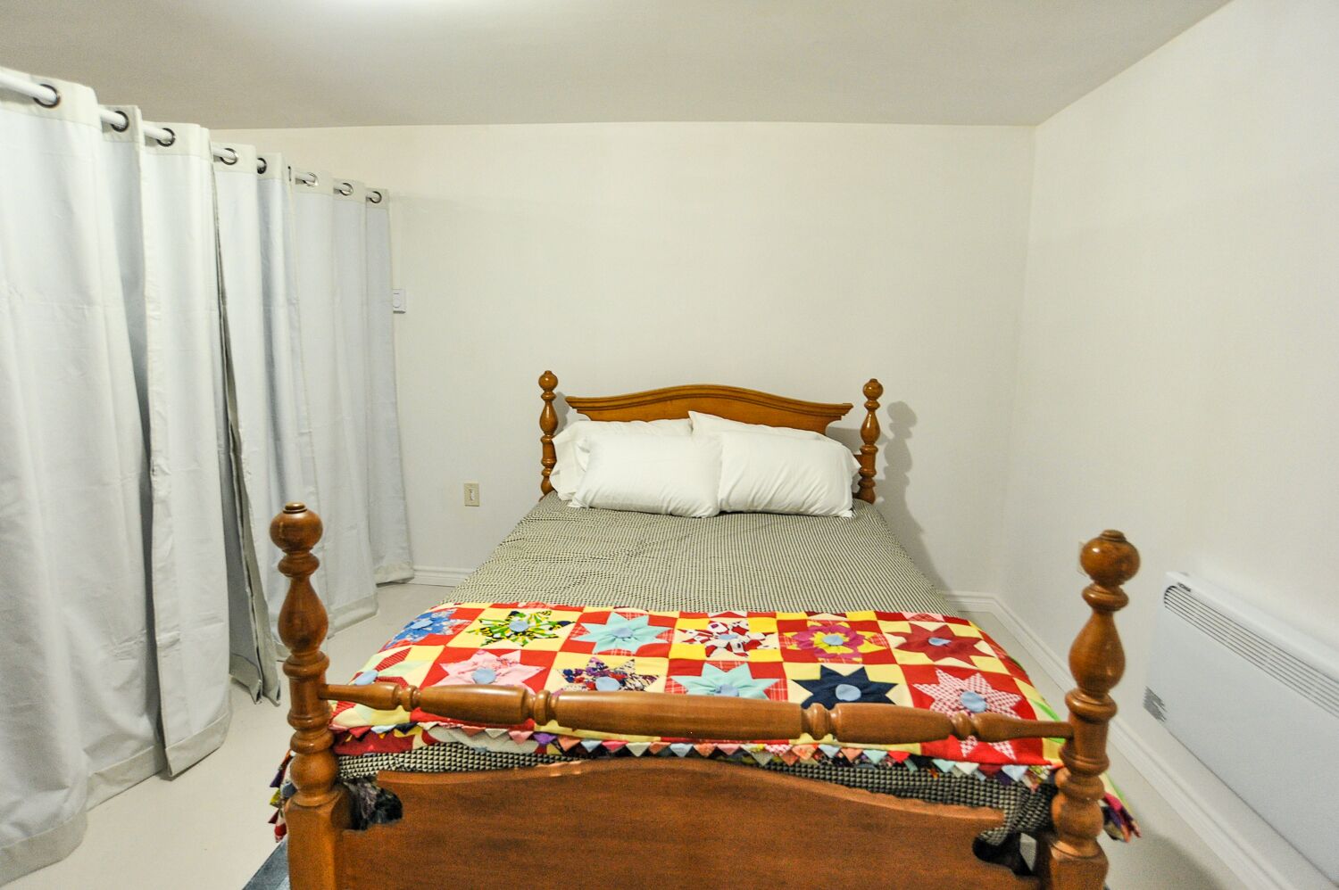 A single bed with a wooden headboard and a colorful quilt.