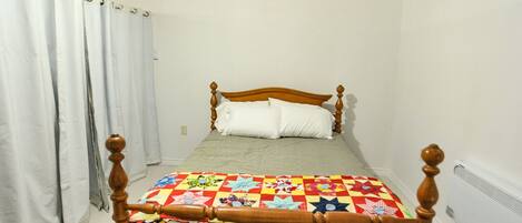 A single bed with a wooden headboard and a colorful quilt.