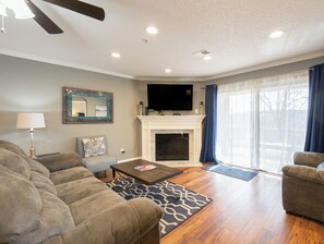 A living room with a fireplace, two sofas, a coffee table, and a television.