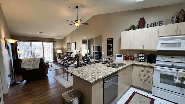 A modern kitchen with a central island, stainless steel appliances, and a dining area with a sofa and table.