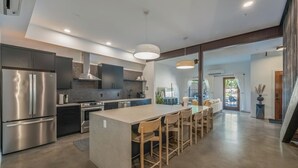 A modern kitchen with a central island, stainless steel appliances, and a dining area with wooden chairs.