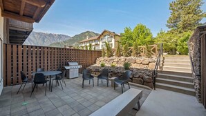 An outdoor patio with a grill, chairs, and a bench.