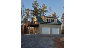 Ein zweigeschossiges Haus mit überdachter Veranda und Garage.
